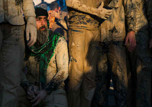 Iranian shiite muslim men gather around a bonfire after rubbing mud on their clothes during the Kharrah Mali ritual to mark the Ashura day, Lorestan Province, Khorramabad, Iran