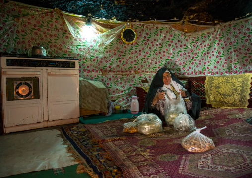 old widow woman in her troglodyte house packing herbs, Kerman province, Meymand, Iran