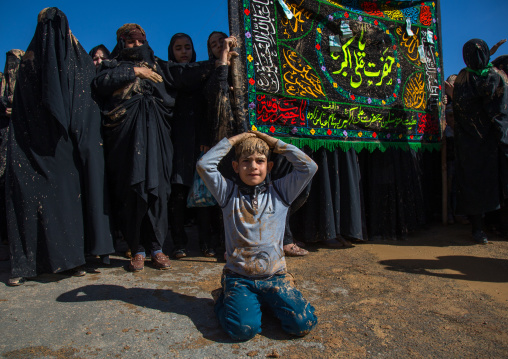 Iranian Shiite Muslim Women Covered In Mud In Front Of A Boy Praying On His Knees During Ashura, The Day Of The Death Of Imam Hussein, Kurdistan Province, Bijar, Iran