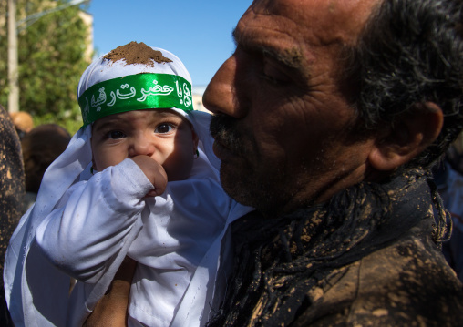 Iranian Shiite Man Covered In Mud Holding His Baby During Ashura Day, Kurdistan Province, Bijar, Iran