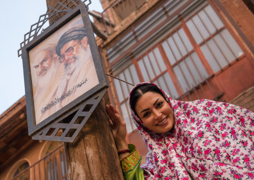 Iranian Woman Wearing Traditional Floreal Chador In Zoroastrian Village In Front Of Khameini And Khomeini Posters, Isfahan Province, Abyaneh, Iran