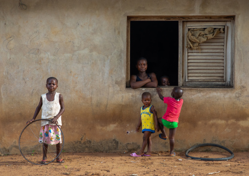 African mother looking thru her window house her children playing, Région des Lacs, Bomizanbo, Ivory Coast