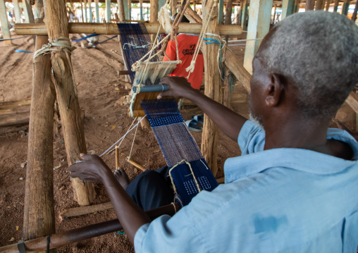 African man from Senufo tribe weaving in a traditional textile factory, Savanes district, Waraniene, Ivory Coast