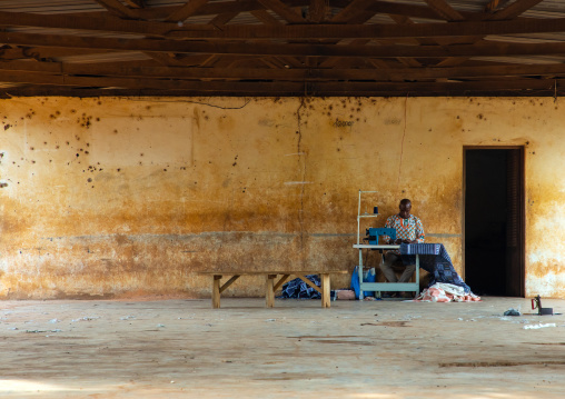 A Senufo vendor with his sewing machine offers his services outdoors, Savanes district, Waraniene, Ivory Coast