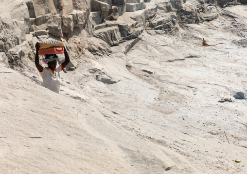 African woman carrying stones in a granite quarry, Savanes district, Shienlow, Ivory Coast