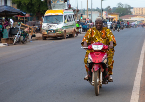 African man riding a motorbike in the street, Poro region, Korhogo, Ivory Coast