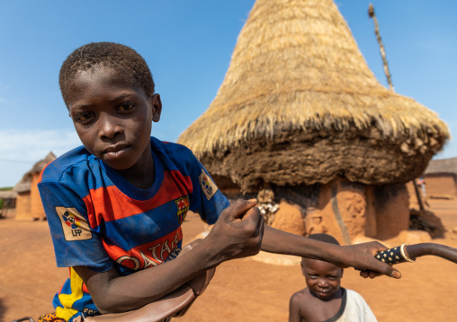 African boy in front of a Senufo fetish house whose roof gets a new layer every year, Savanes district, Niofoin, Ivory Coast