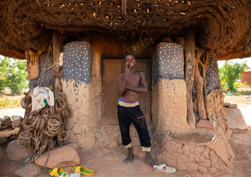 African man standing at the entrance of a Senufo fetish house, Savanes district, Niofoin, Ivory Coast