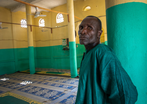 African man in green clothes inside a mosque, Denguélé, Korondougou, Ivory Coast