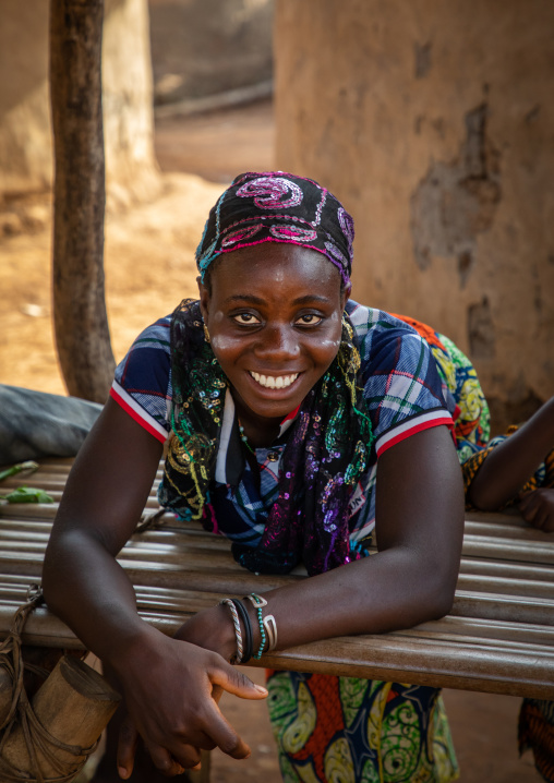 Portrait of a Dan tribe smiling woman resting on a wood bed, Bafing, Gboni, Ivory Coast
