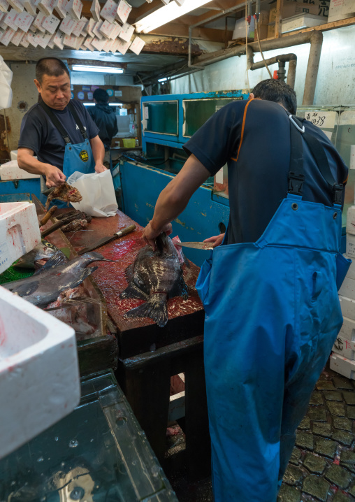 Vendor slicing fish at the tsukiji fish market, Kanto region, Tokyo, Japan