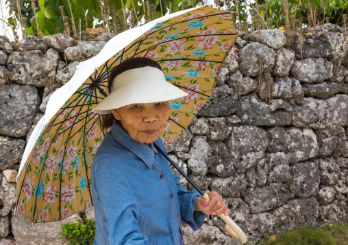 Senior japanese woman with an umbrella, Yaeyama Islands, Taketomi island, Japan