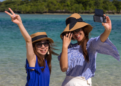 Japanese girls taking selfie in the tropical lagoon with clear blue water in Kabira bay, Yaeyama Islands, Ishigaki, Japan