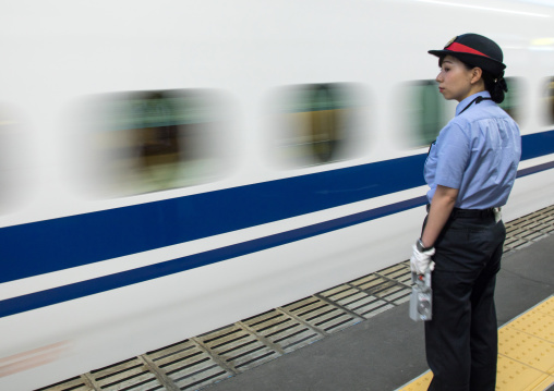 Japanese female station master in front of a Shinkansen train in a station, Hypgo Prefecture, Himeji, Japan
