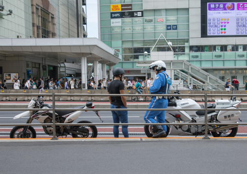 Police control traffic with a motorbike driver, Kanto region, Tokyo, Japan