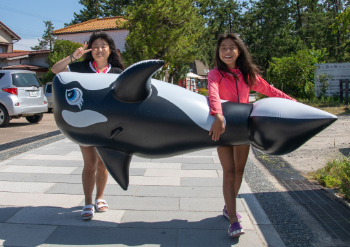 Japanese tourists carrying an orca shaped inflatable ring in Amanohashidate sanbar, Kyoto Prefecture, Miyazu, Japan