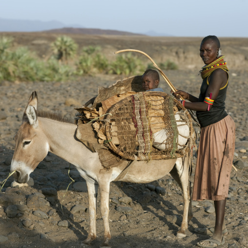 Rendille tribe woman with her baby sit a donkey, Rift Valley Province, Turkana lake, Kenya