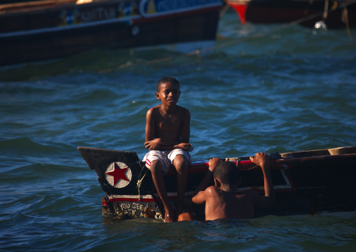 Boys playing on a boat and in the sea, Lamu County, Lamu, Kenya