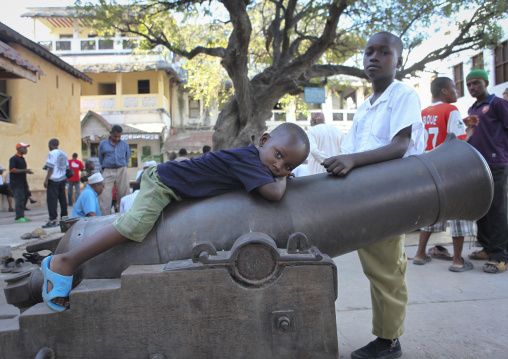 Little boy lazing on a cannon, Lamu County, Lamu, Kenya