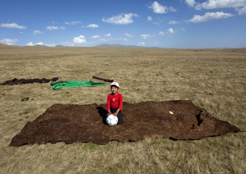 Boy Sitting On The Skin Floor Carpet Of His Yurt, Song Kol Lake Area, Kyrgyzstan