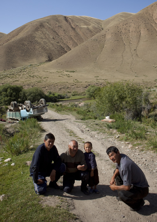 Men And Boys Crouching On The Road Near Their Overturned Truck, Kyrgyzstan