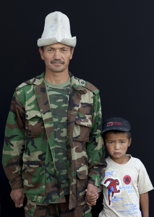 Father With Kalpak Hat And With His Son Wearing A Cap, Kochkor Animal Market, Kyrgyzstan