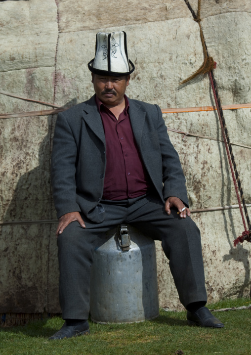 Man With Kalpak Hat Sitting On A Milk Jug, Saralasaz Jailoo, Kyrgyzstan