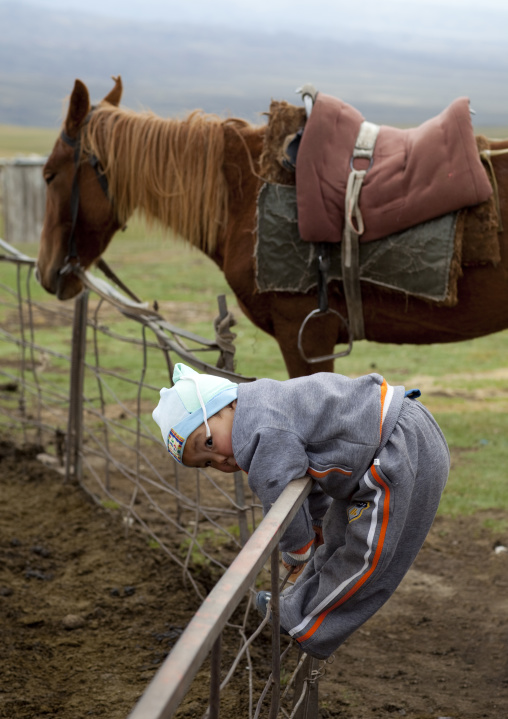 Baby Clinging To A Fence And Horse, Saralasaz Jailoo, Kyrgyzstan