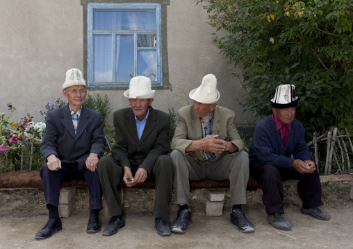 Old Men With Kalpak Hats Sitting On A Bench, Kochkor, Kyrgyzstan