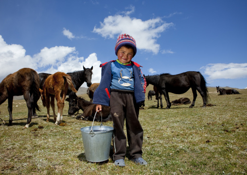 Boy Holding A Bucket In Front Of Horses, Song Kol Lake Area, Kyrgyzstan
