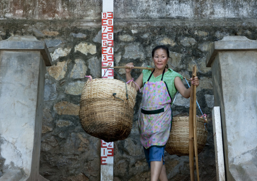Woman carrying baskets on the banks of the mekong, Luang prabang, Laos