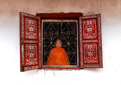 Novice buddhist monk in front of a window in a temple, Nam deng, Laos