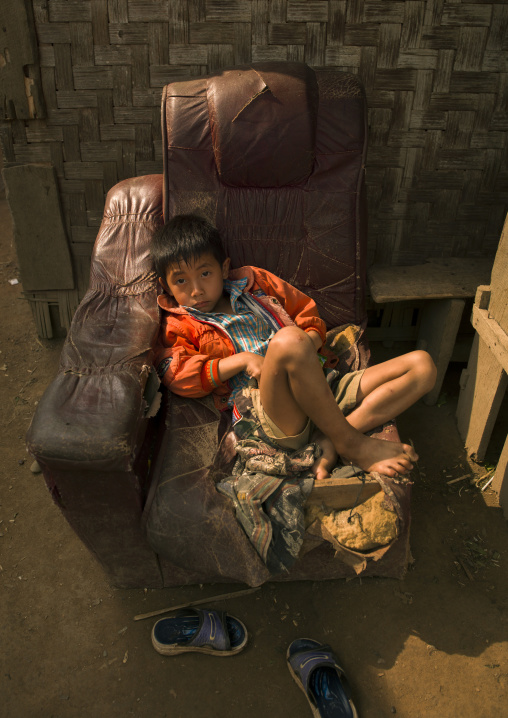 Boy sitting in an old chair, Louang namtha, Laos