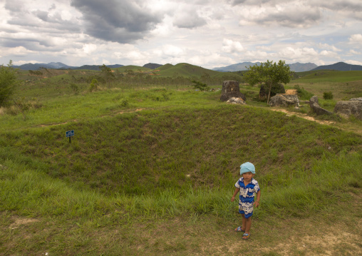 Child in from of a bomb crater at plain of jars, Phonsavan, Laos