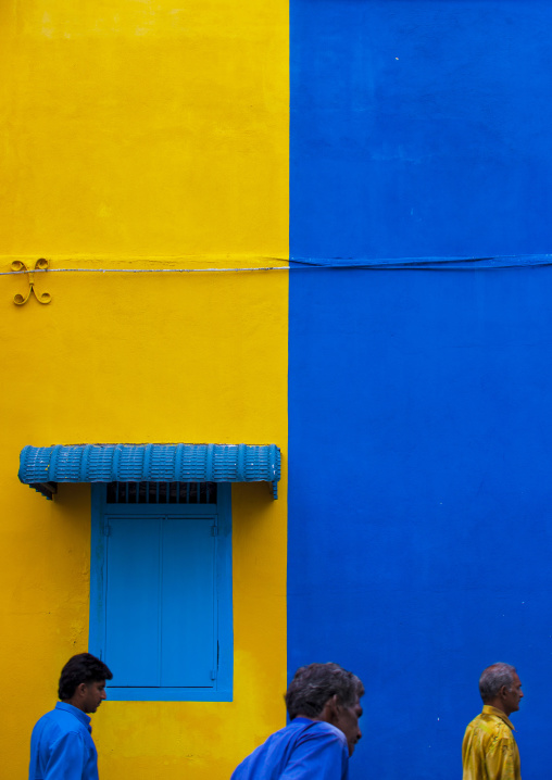 Men Passing In Front Of Yellow And Blue Wall In The Street, George Town, Penang, Malaysia