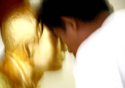 Man Praying In Front Of A Golden Statue In Shwedagon Pagoda, Rangoon, Myanmar