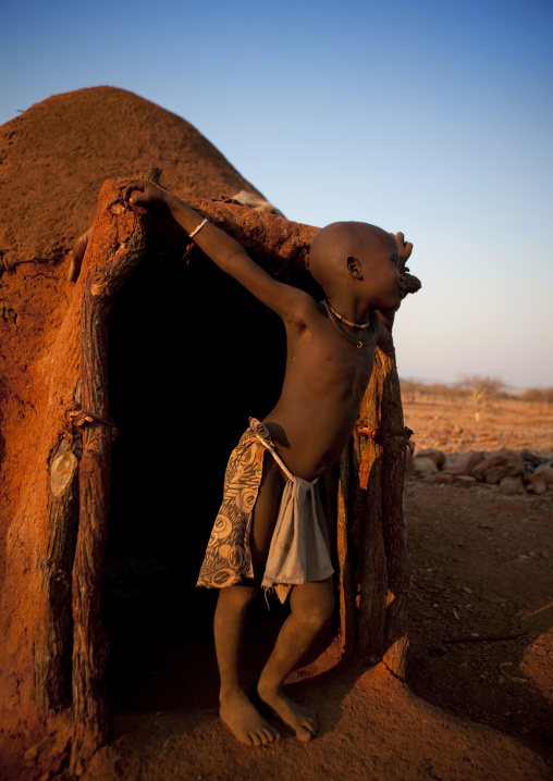 Himba Boy In The Entrance Of His Hut, Okapale Area, Namibia