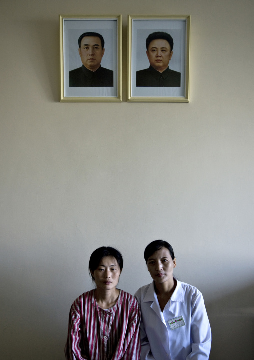 North Korean doctor and patient in a maternity under the official portraits of the Dear Leaders, Pyongan Province, Pyongyang, North Korea