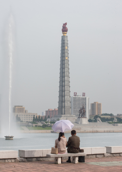A North Korean soldier with his wife sitting on a bench in front of the Juche tower, Pyongan Province, Pyongyang, North Korea
