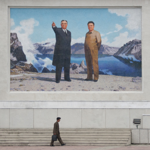 North Korean man passing in front of a giant fresco of Kim il and Sung Kim Jong il, Kangwon Province, Wonsan, North Korea
