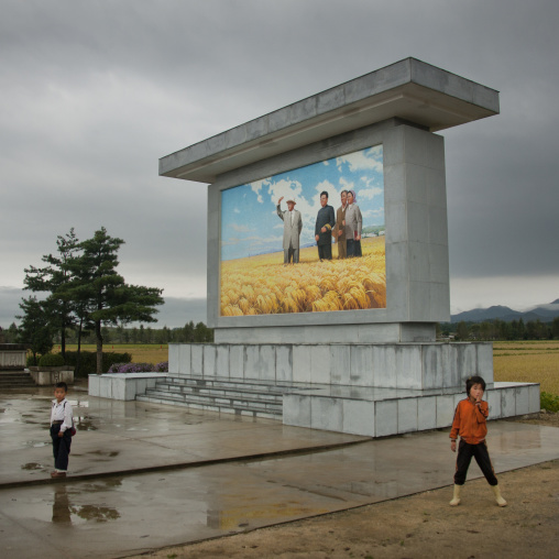 North Korean children in front of a fresco of the Dear Leaders with farmers, South Hamgyong Province, Hamhung, North Korea
