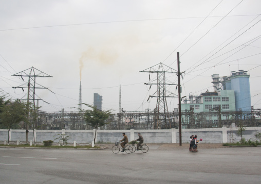 North Korean people on bicycles passing in front a chemical factory, South Hamgyong Province, Hamhung, North Korea