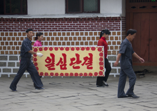 North Korean people carrying a propaganda bilboard i the street, North Hwanghae Province, Kaesong, North Korea