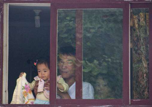 North Korean man holding her daughter through window frame, North Hwanghae Province, Kaesong, North Korea