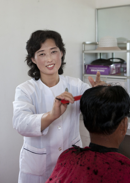 Smiling North Korean hairdresser cutting hair, South Pyongan Province, Chongsan-ri Cooperative Farm, North Korea
