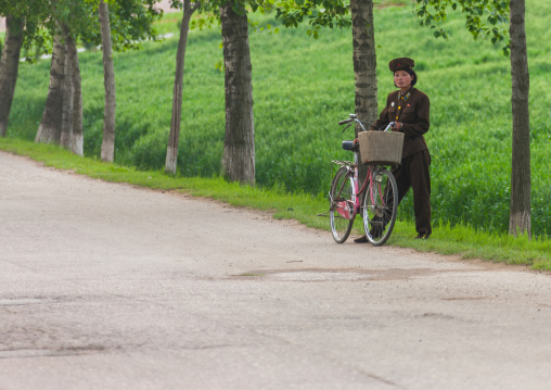 North Korean female soldier with her bicycle on the side of the road, South Pyongan Province, Nampo, North Korea