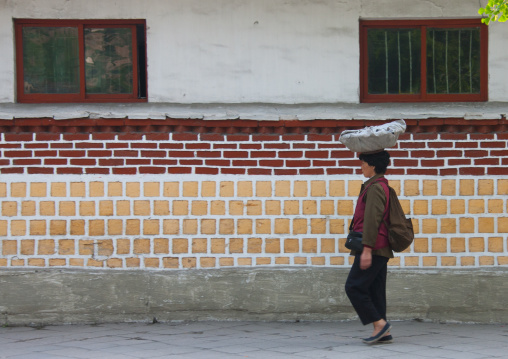 North Korean woman carrying stuff on her head in the street, North Hwanghae Province, Kaesong, North Korea