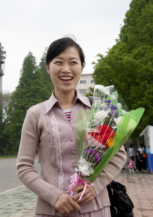 Smiling North Korean woman with a bunch of flowers in Mansudae Grand monument, Pyongan Province, Pyongyang, North Korea
