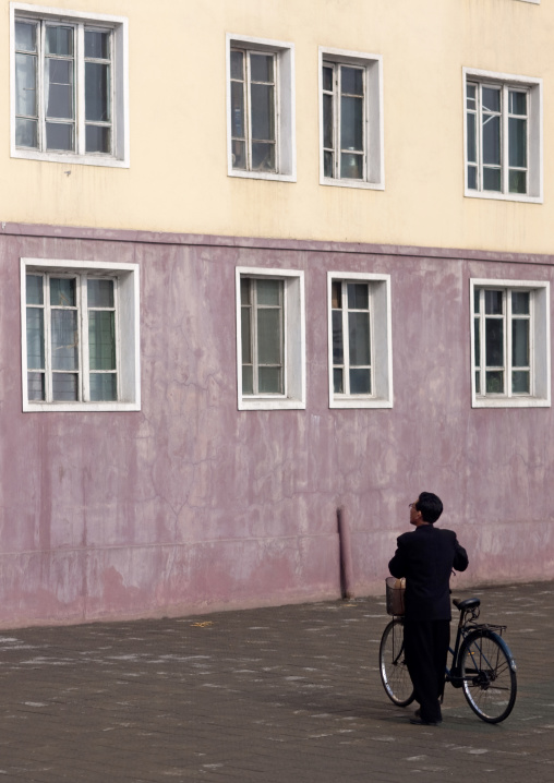 North Korean man with a bicycle speaking to someone in a building, Pyongan Province, Pyongyang, North Korea
