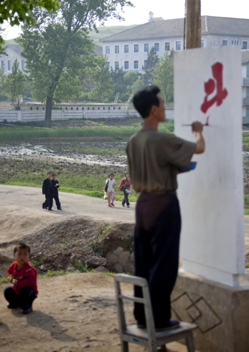 North Korean man painting a propaganda billboard in the countryside, North Hwanghae Province, Kaesong, North Korea